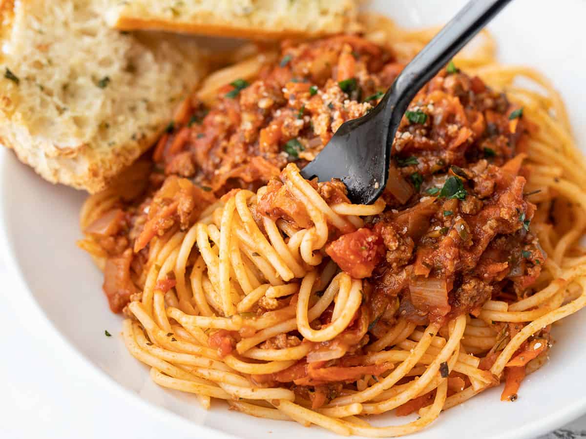 Gros plan d'une fourchette tourbillonnant spaghetti avec sauce pour pâtes aux légumes cachés