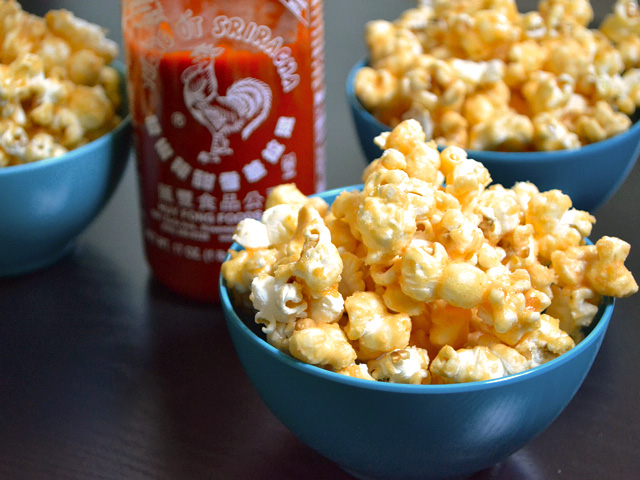Trois bols de Sriracha Caramel Corn avec une bouteille de siracha 