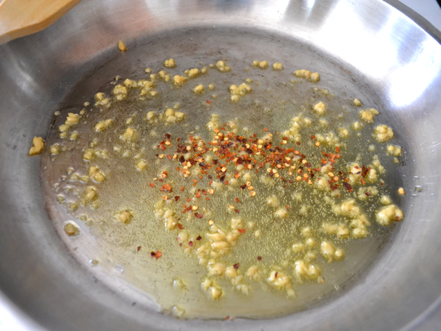 poivron rouge broyé ajouté à l'huile d'olive et à l'ail dans une poêle 