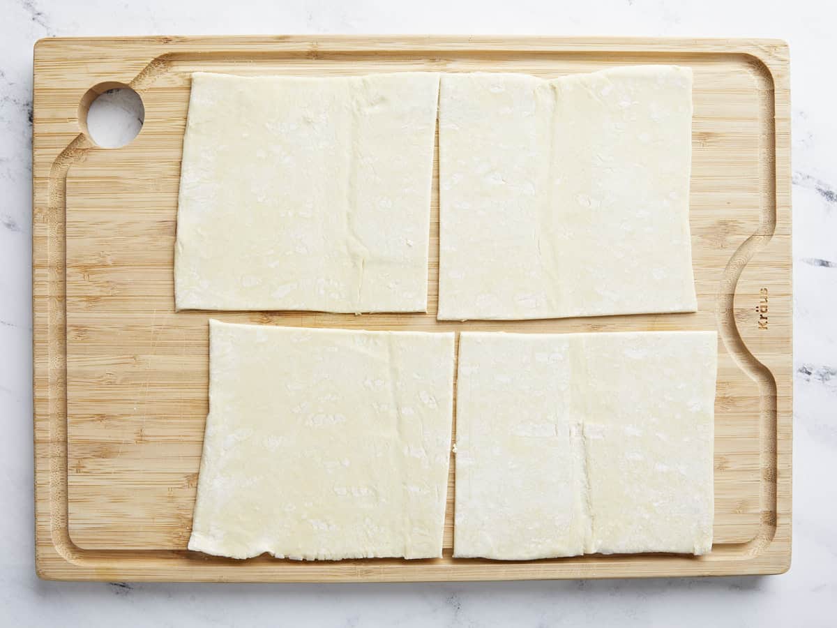 Pâte feuilletée coupée en carrés sur une planche à découper.