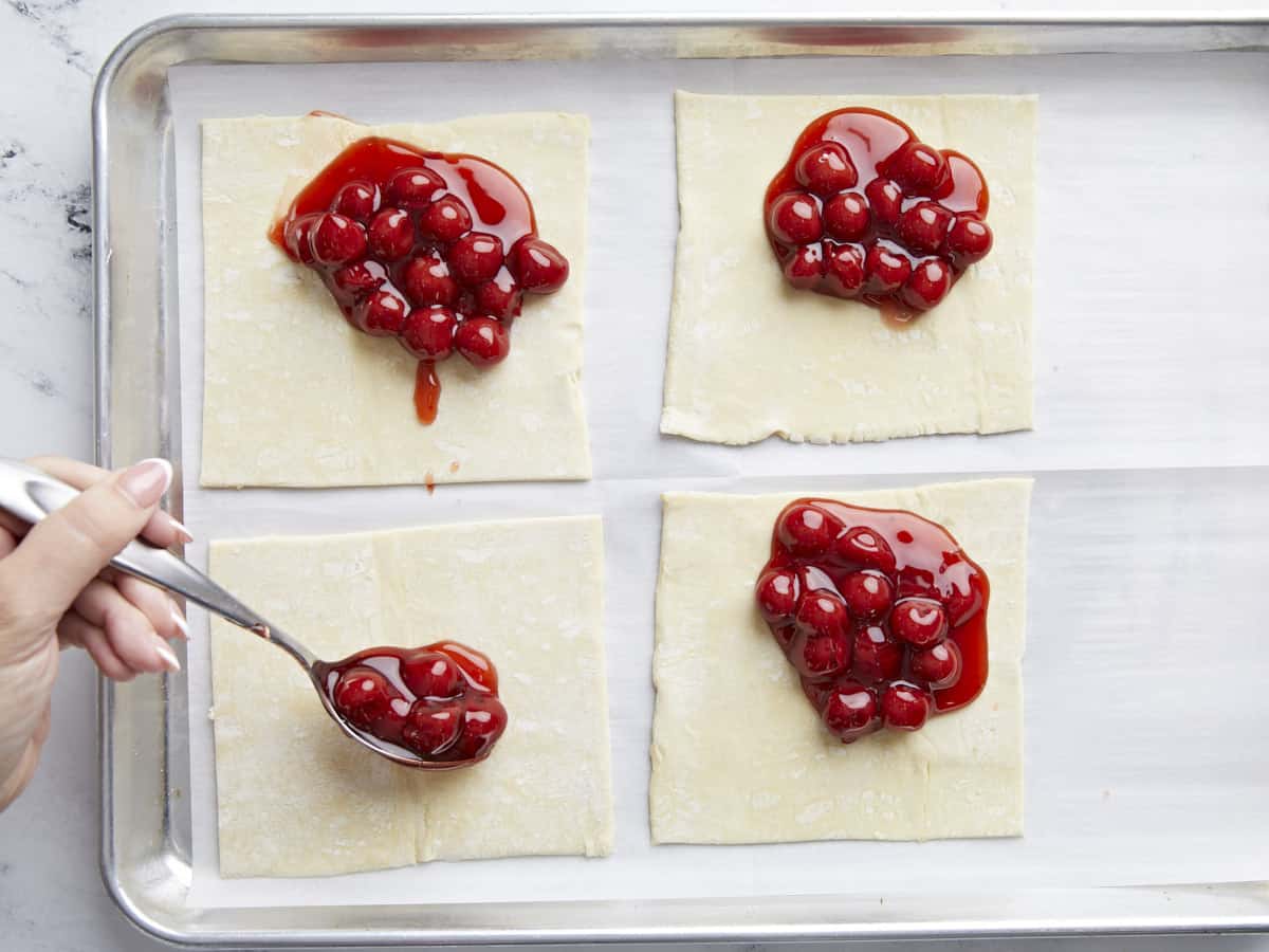 Garniture aux cerises déposée sur des carrés de pâte feuilletée.