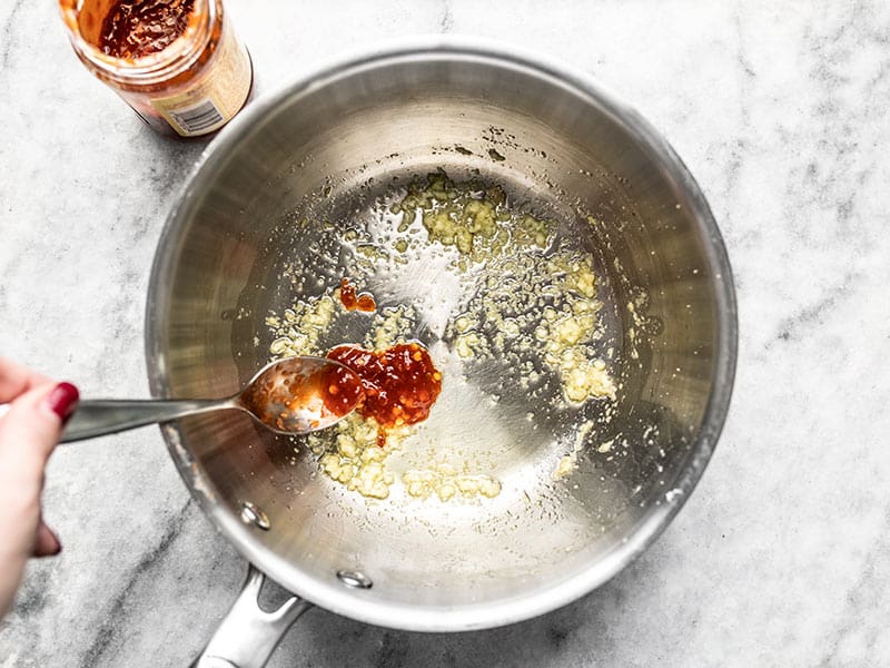 Un bouquet de nouilles retiré du bol de ramen amélioré avec des baguettes.