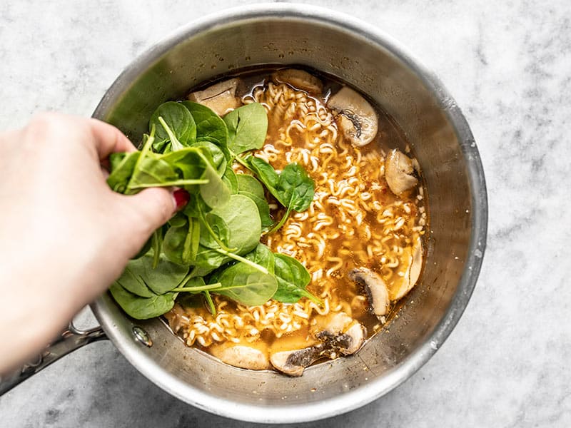 Les épinards sont ajoutés aux ramen cuits dans la casserole.