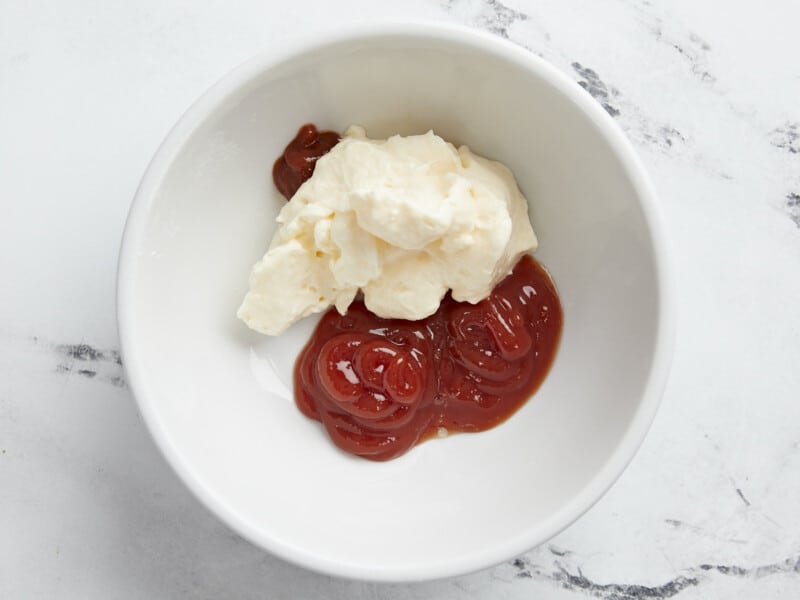 Plan aérien des ingrédients du Mayo Ketchup dans un petit bol blanc entouré de tostones.