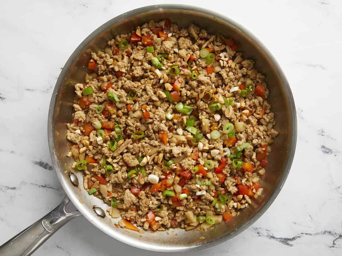 Poulet fini et légumes avec oignons verts et cacahuètes hachées saupoudrées sur le dessus.