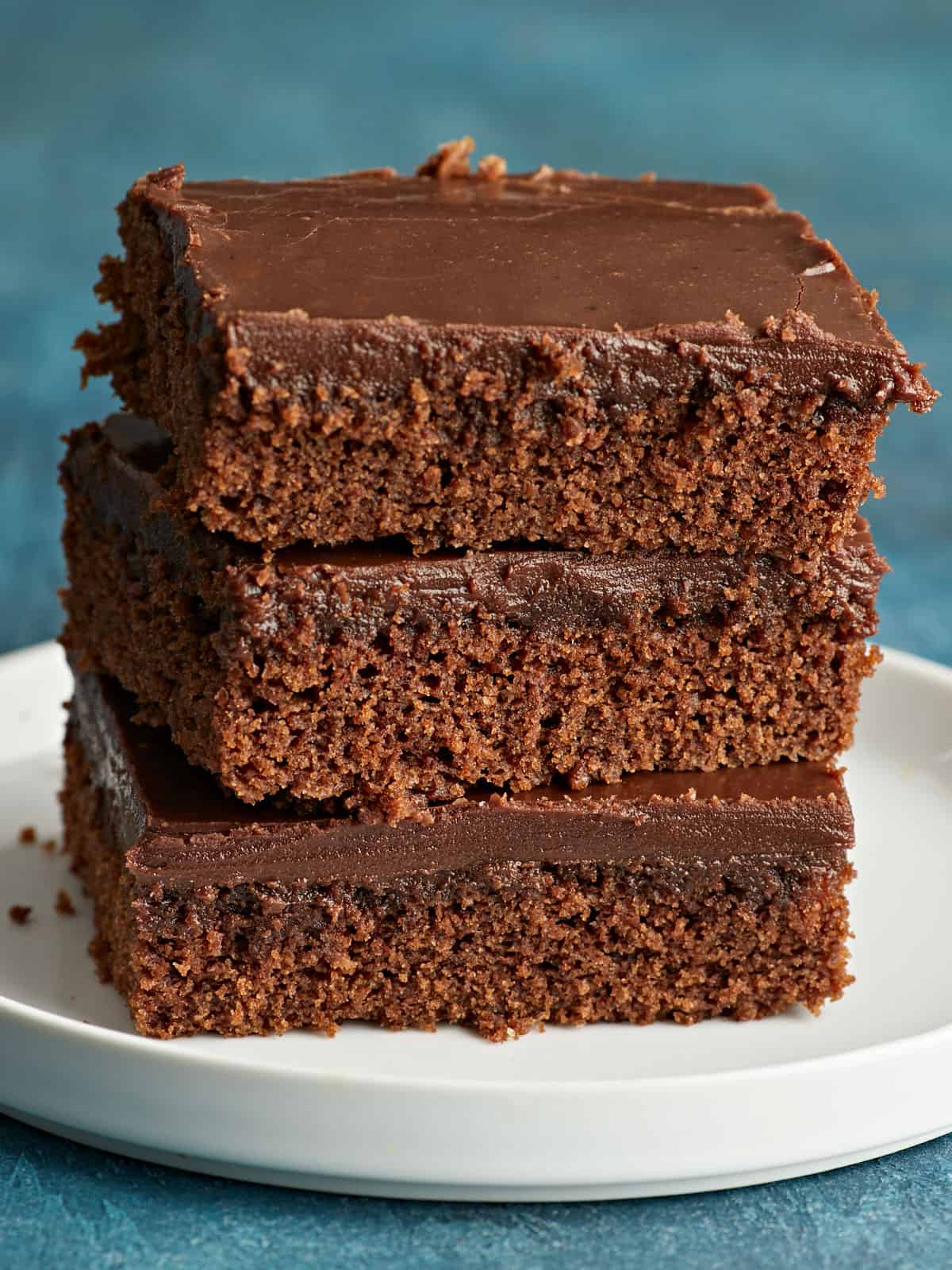Une pile de trois tranches de gâteau au chocolat sur une assiette.