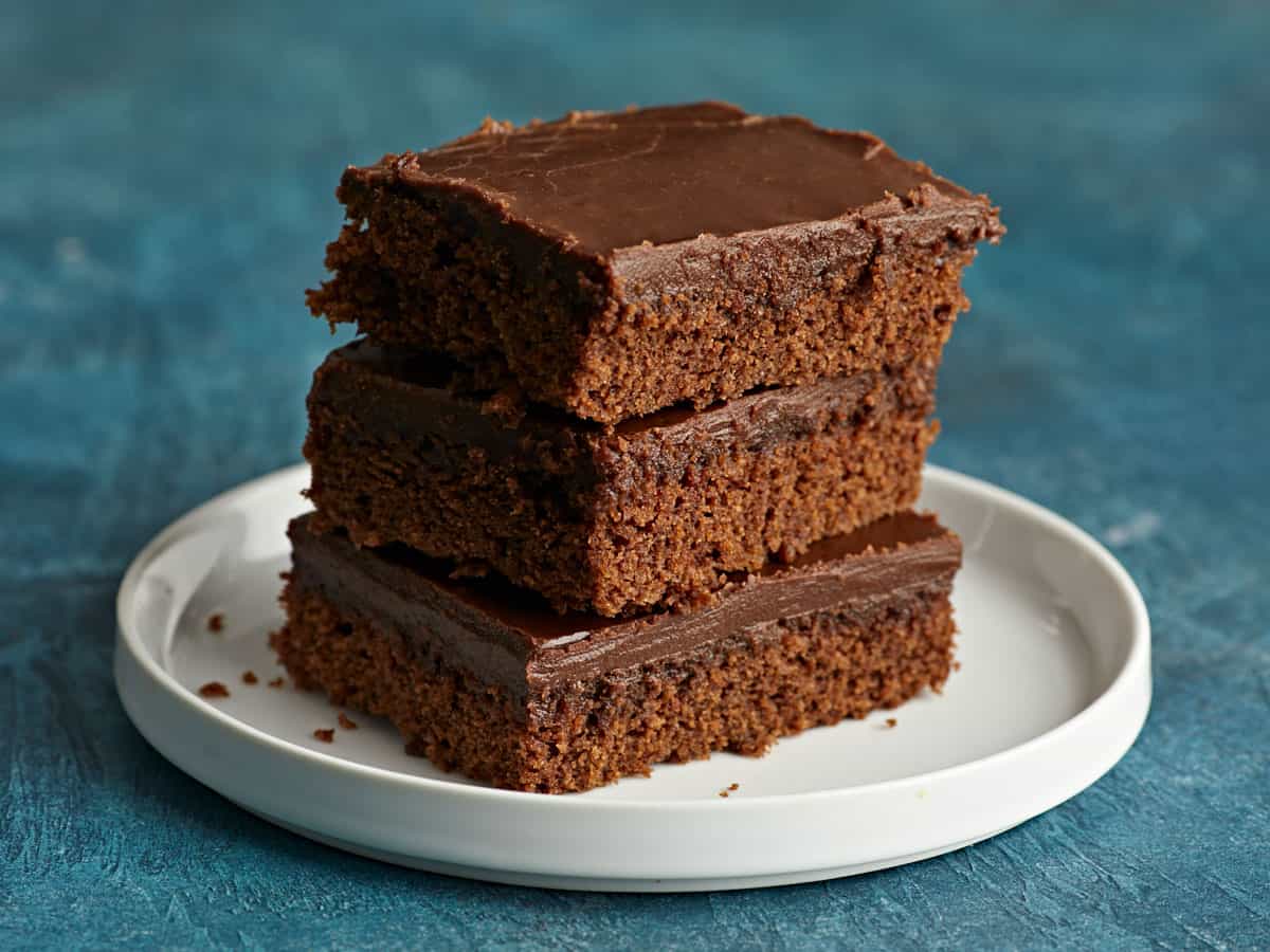 Trois tranches de gâteau au chocolat sur une assiette, empilées.
