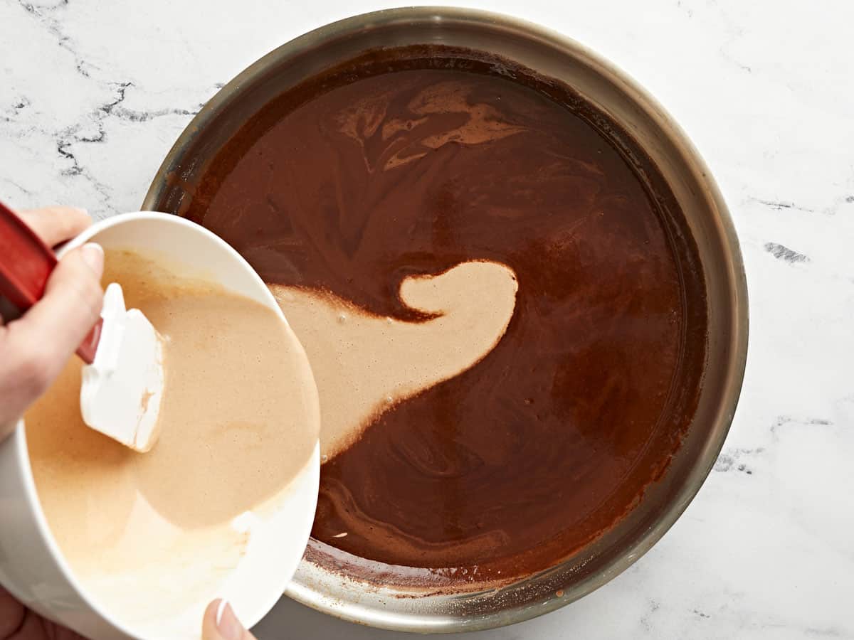 Mélange d'œufs ajouté au chocolat chaud dans la poêle.