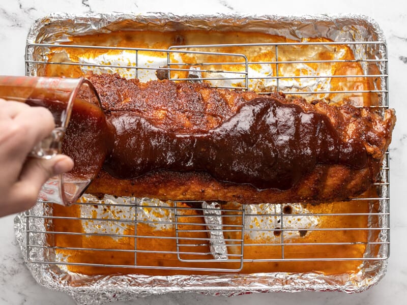 Ajouter la sauce barbecue aux côtes levées cuites sur une grille.