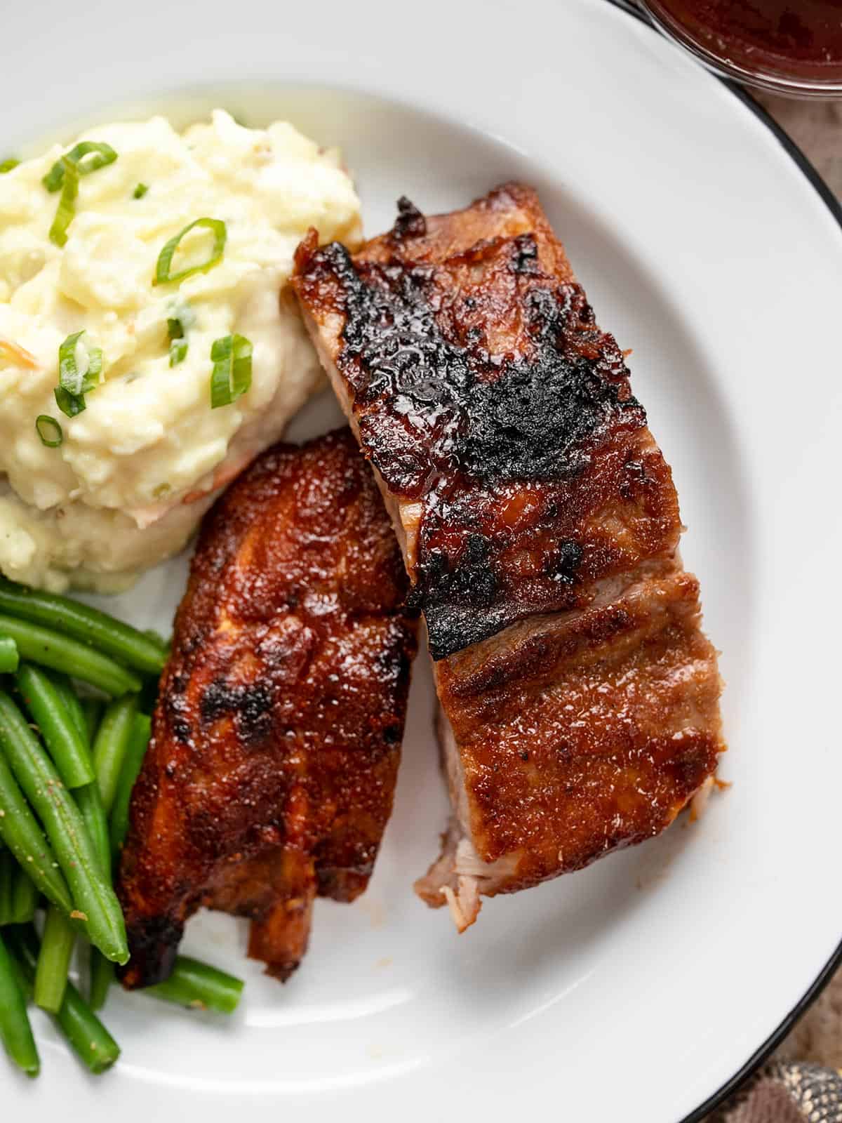 Couper les côtes levées sur une assiette blanche avec de la purée de pommes de terre et des haricots verts.