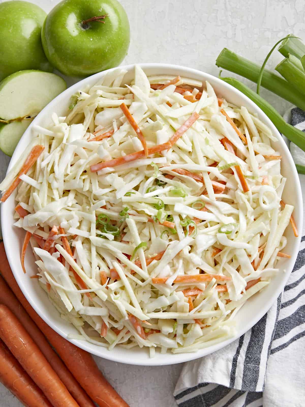 Vue aérienne d'un bol rempli de salade de pommes avec des ingrédients sur les côtés.
