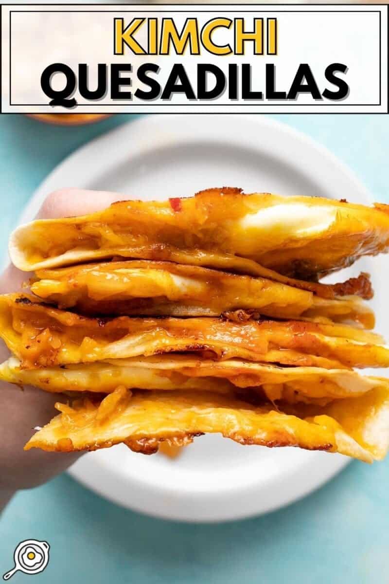 Vue rapprochée d'une main tenant une pile de quesadillas au kimchi.