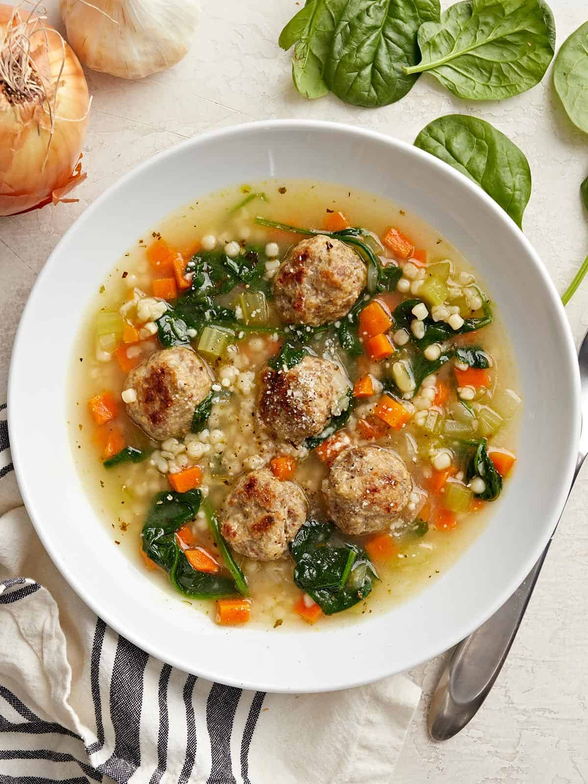 Vue aérienne d'un bol rempli de soupe de mariage italienne avec du pain sur le côté.