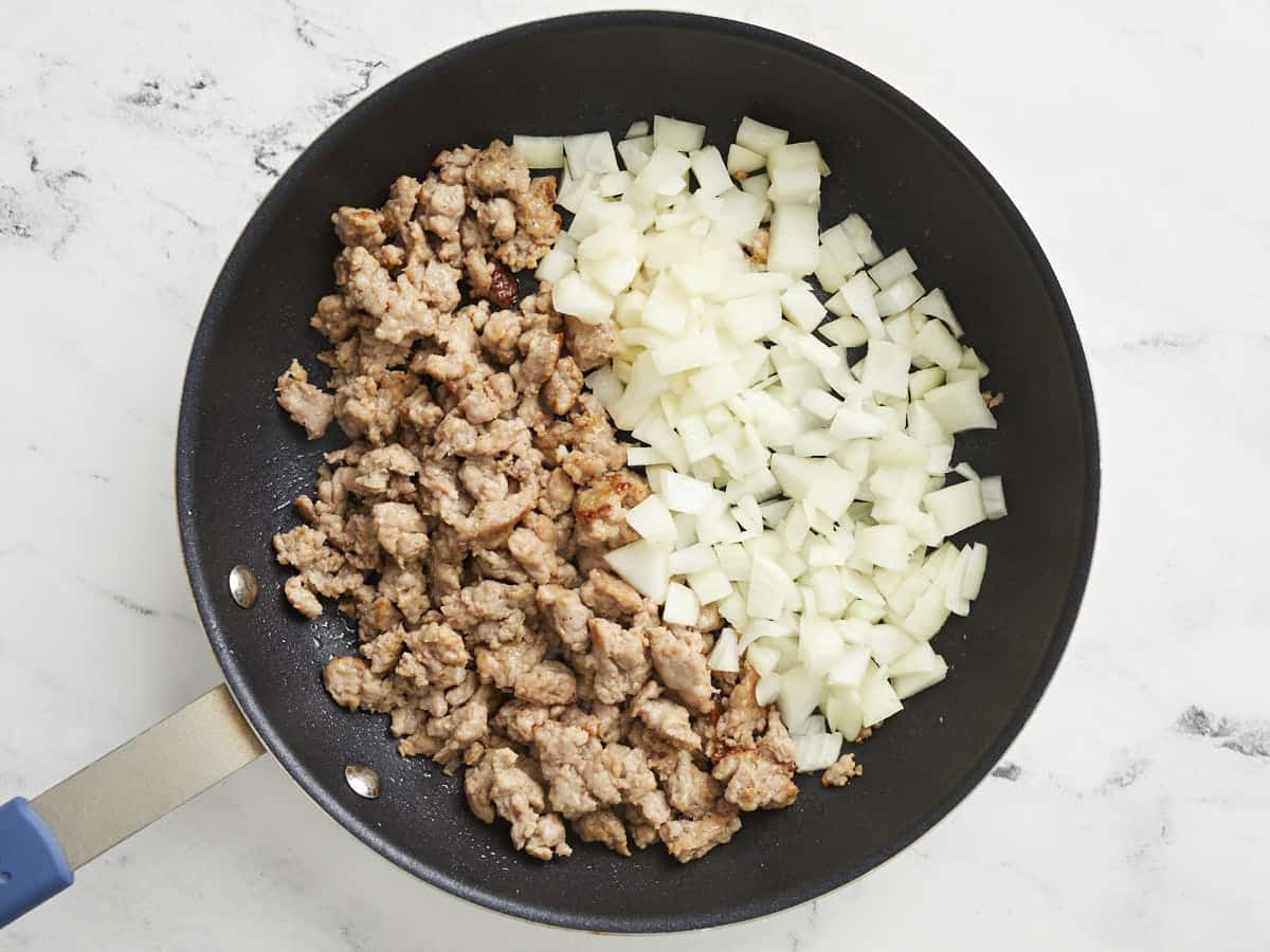 Saucisse hachée et oignons coupés en dés dans une poêle antiadhésive.