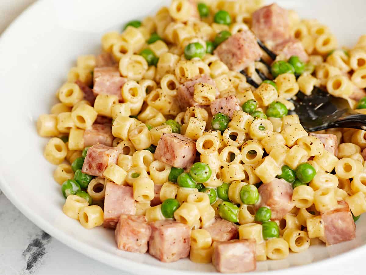 Vue rapprochée d'un bol de pâtes aux petits pois et au jambon.