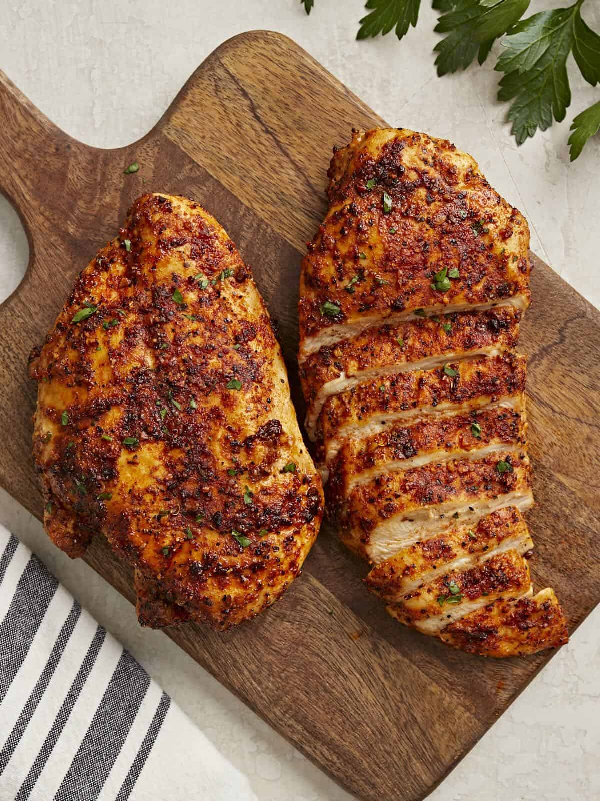 Poitrines de poulet tranchées à la friteuse à air sur une planche à découper en bois.