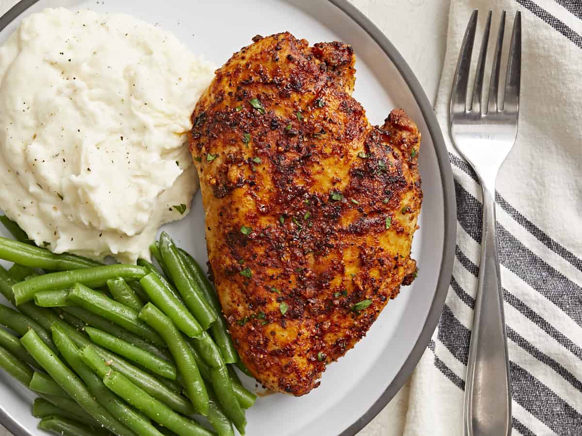 Vue aérienne de la poitrine de poulet Air Fryer sur une assiette avec un côté de purée de pommes de terre et de haricots verts.