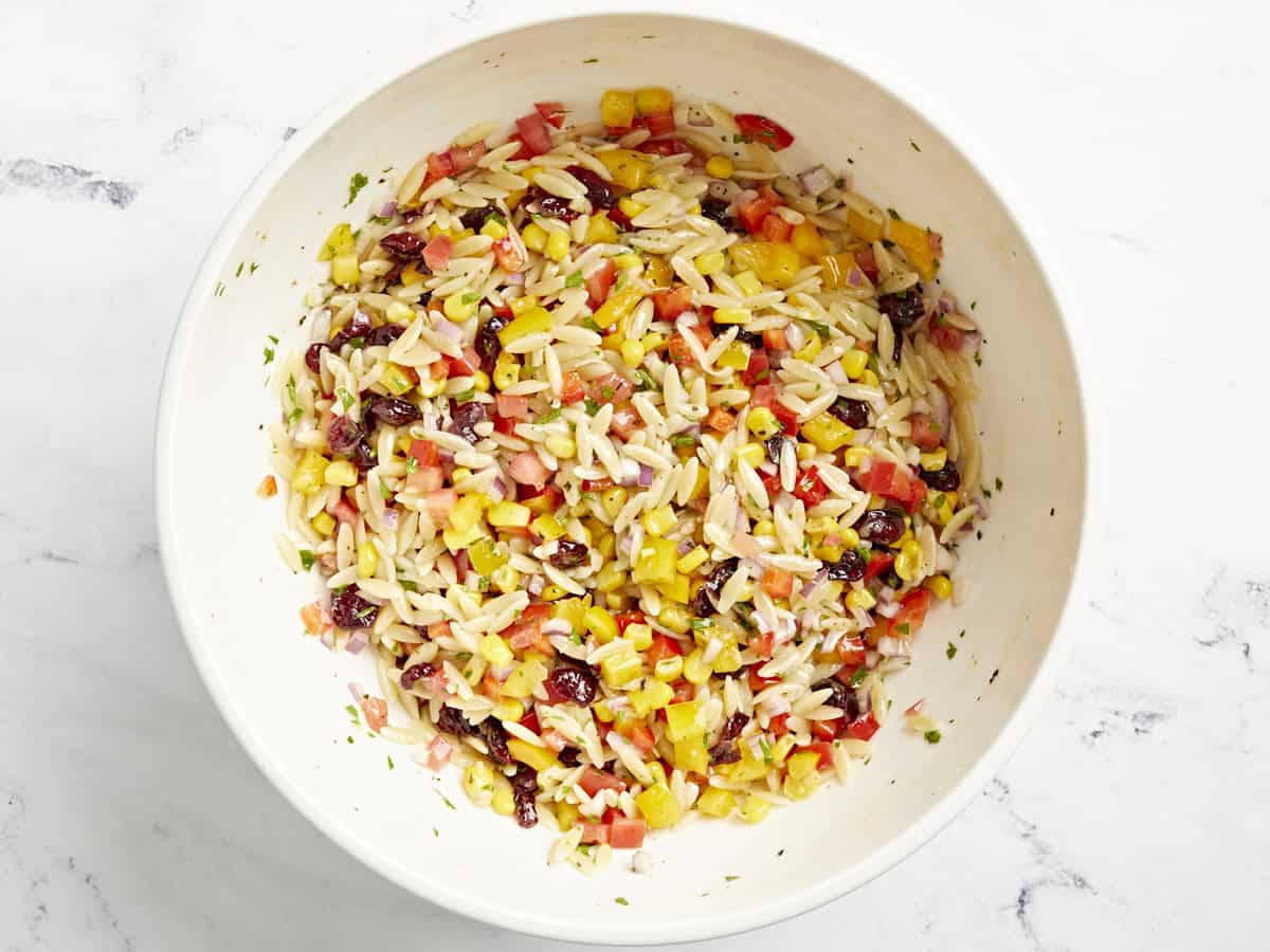 Ingrédients de la salade de pâtes Orzo mélangés dans un grand bol.