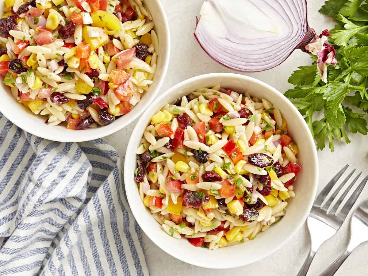 Vue aérienne de deux bols blancs de salade de pâtes orzo.