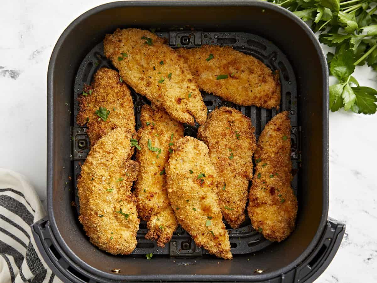 Overhead view of 8 cooked air fryer chicken tenders in an air fryer basket.