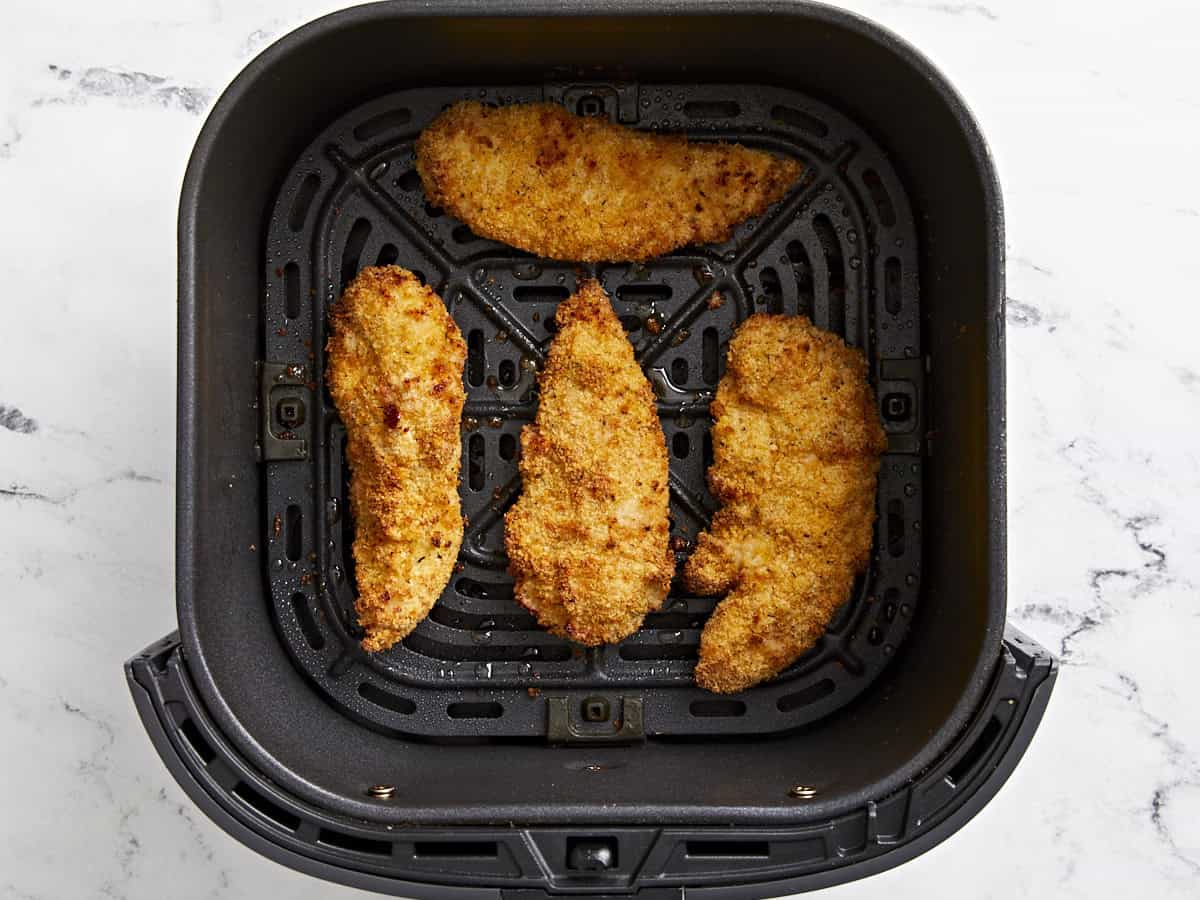 Vue aérienne des offres de poulet cuites dans une friteuse à air dans un panier de friteuse à air.