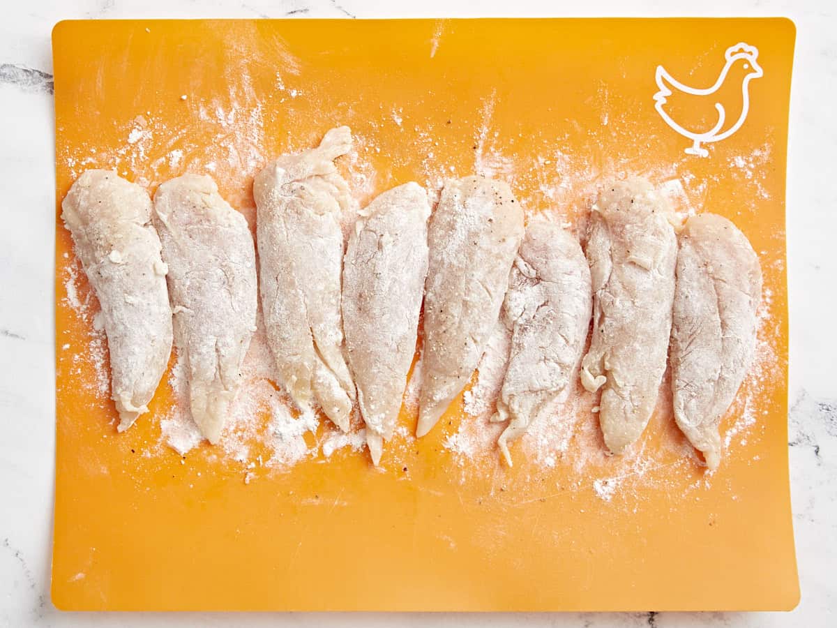 Vue aérienne des offres de poulet mélangées à la farine sur une planche à découper.