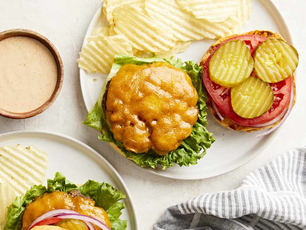 Vue aérienne de hamburgers faits maison sur une assiette avec garnitures et frites sur le côté.