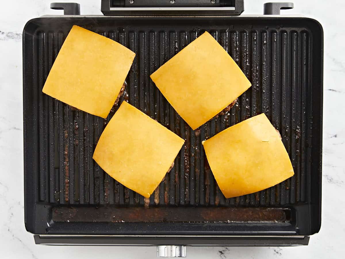 Galettes de hamburger avec du fromage sur le gril.