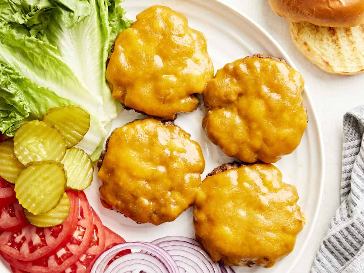 Vue aérienne de hamburgers faits maison sur un plateau de service avec garnitures sur le côté.