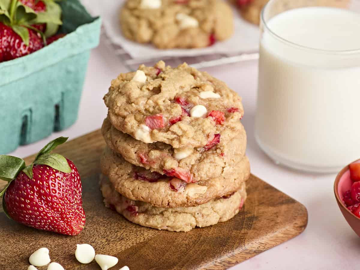 4 biscuits aux fraises empilés sur une planche à découper en bois.