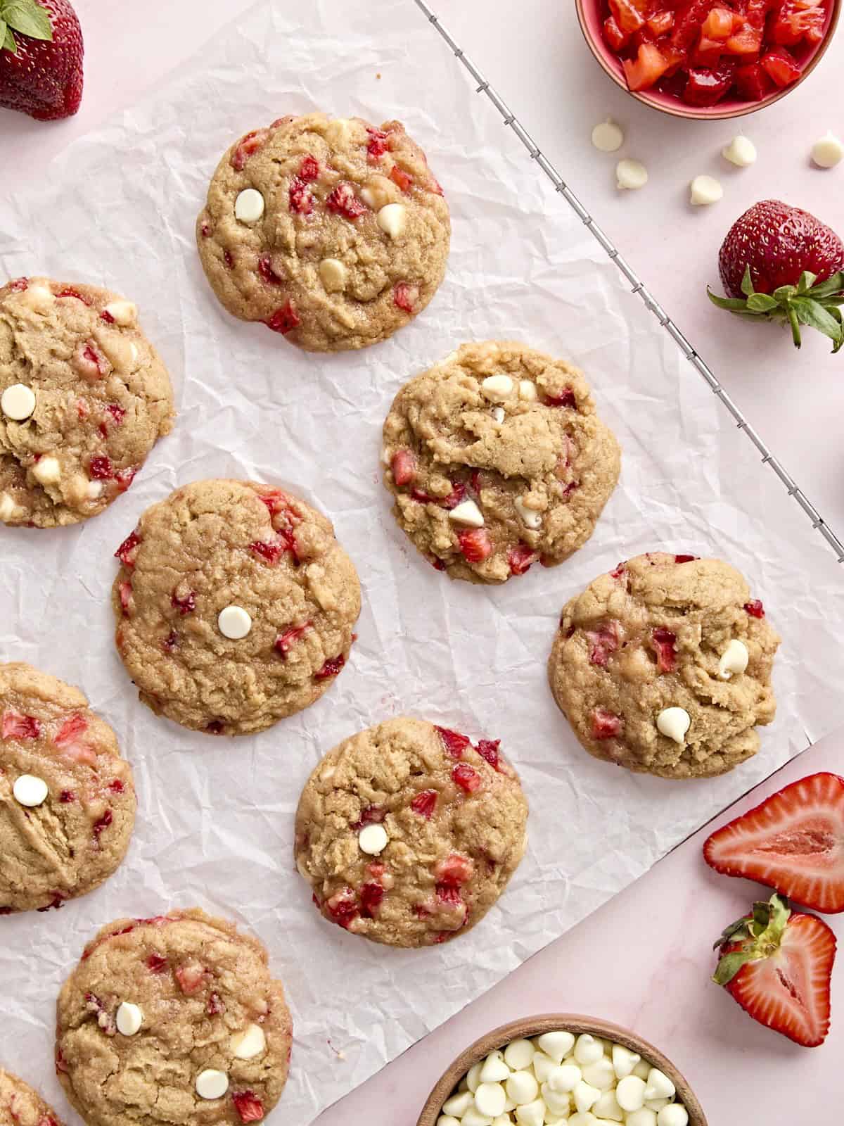 vue aérienne de 12 biscuits aux fraises sur une grille recouverte de papier sulfurisé.