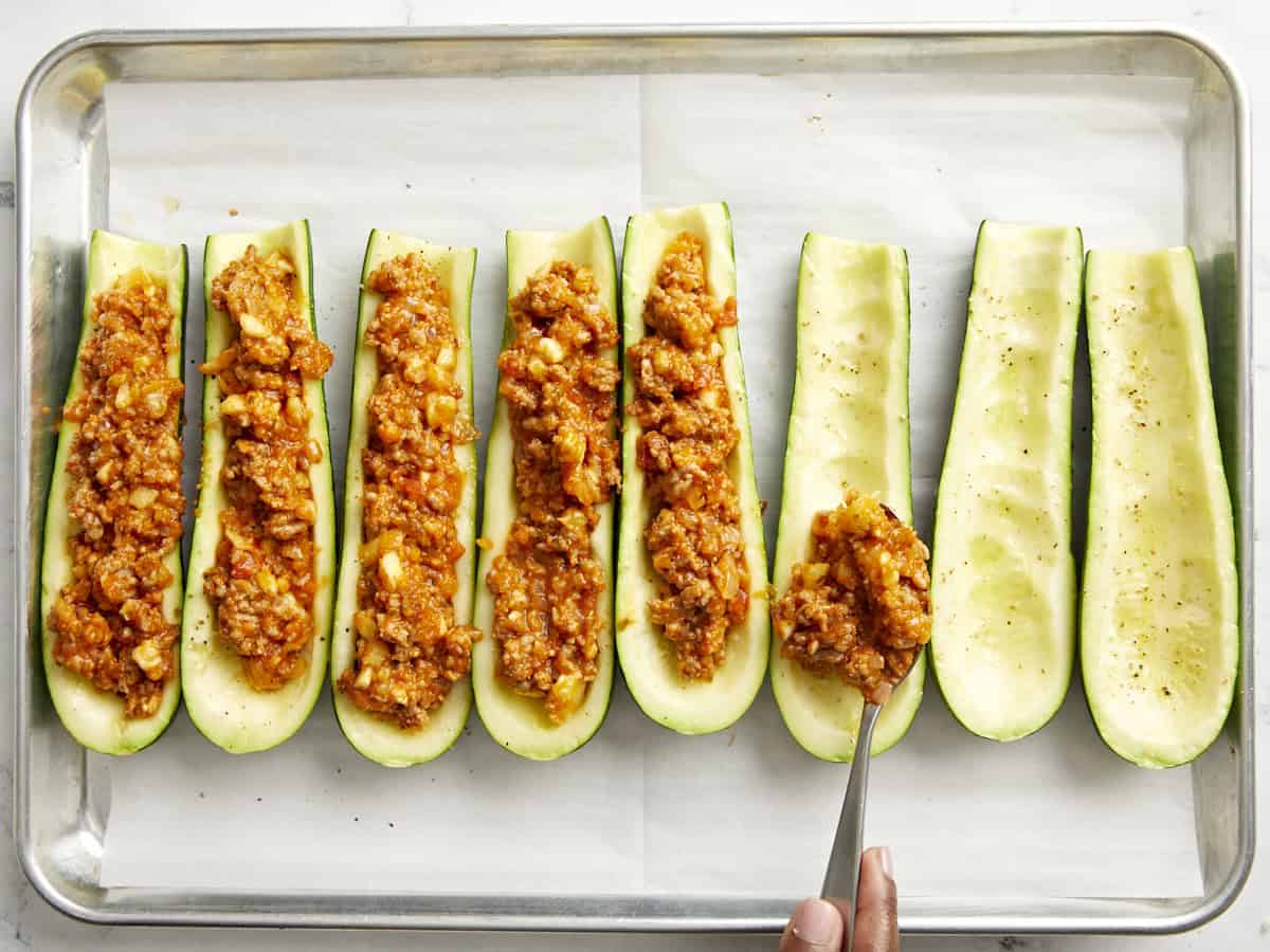 Ajout du mélange de saucisses à l’intérieur des bateaux de courgettes. 