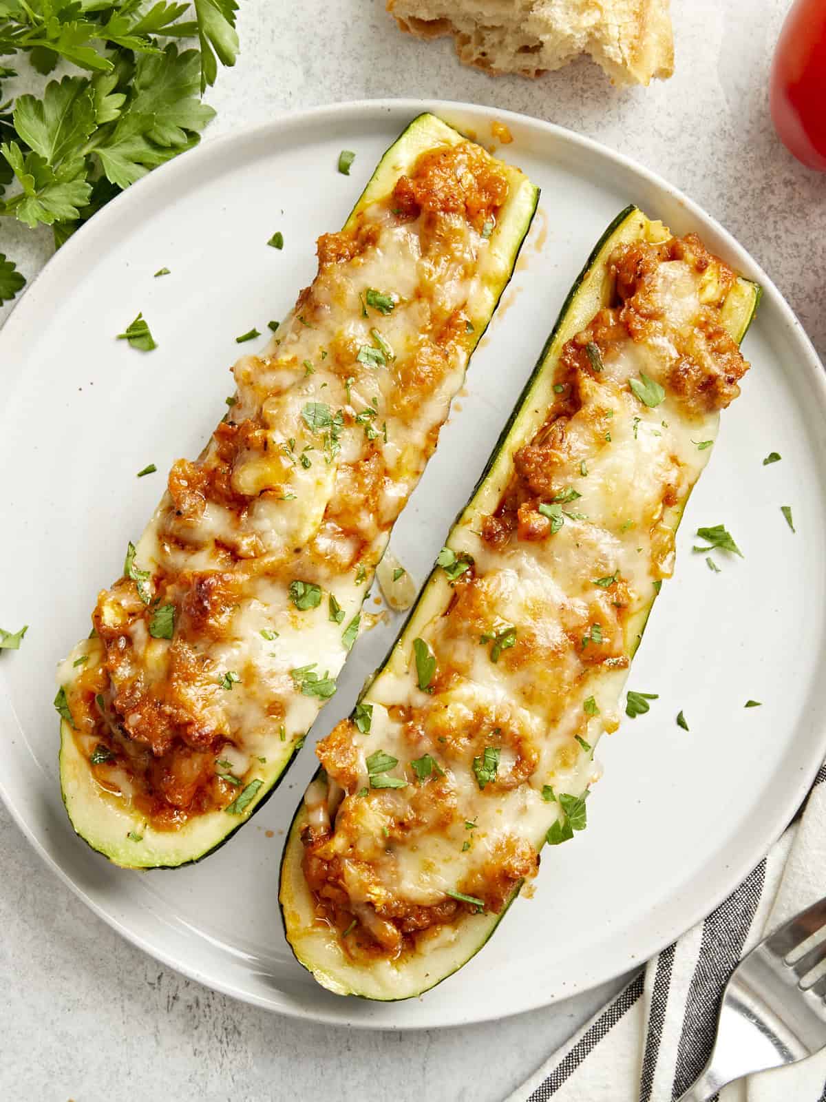 Deux bateaux de courgettes sur une assiette de service avec du persil garni sur le dessus.