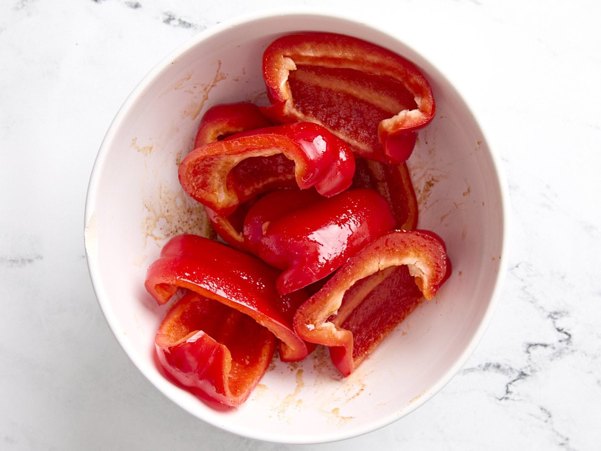 Poivrons coupés en quartiers mélangés à un mélange d'assaisonnements pour tacos au chou-fleur avec sauce romesco