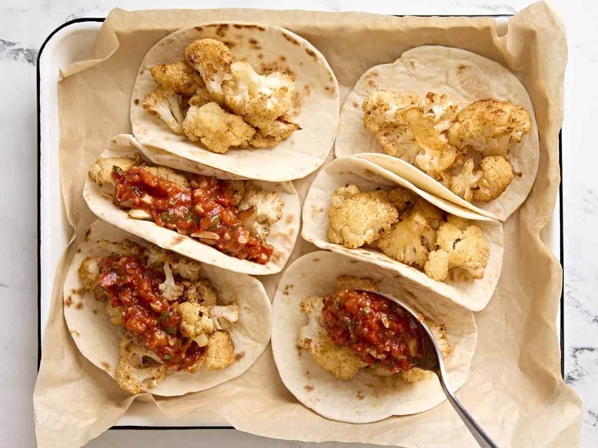 Tacos de chou-fleur à la sauce romesco sur une plaque à pâtisserie recouverte de papier sulfurisé