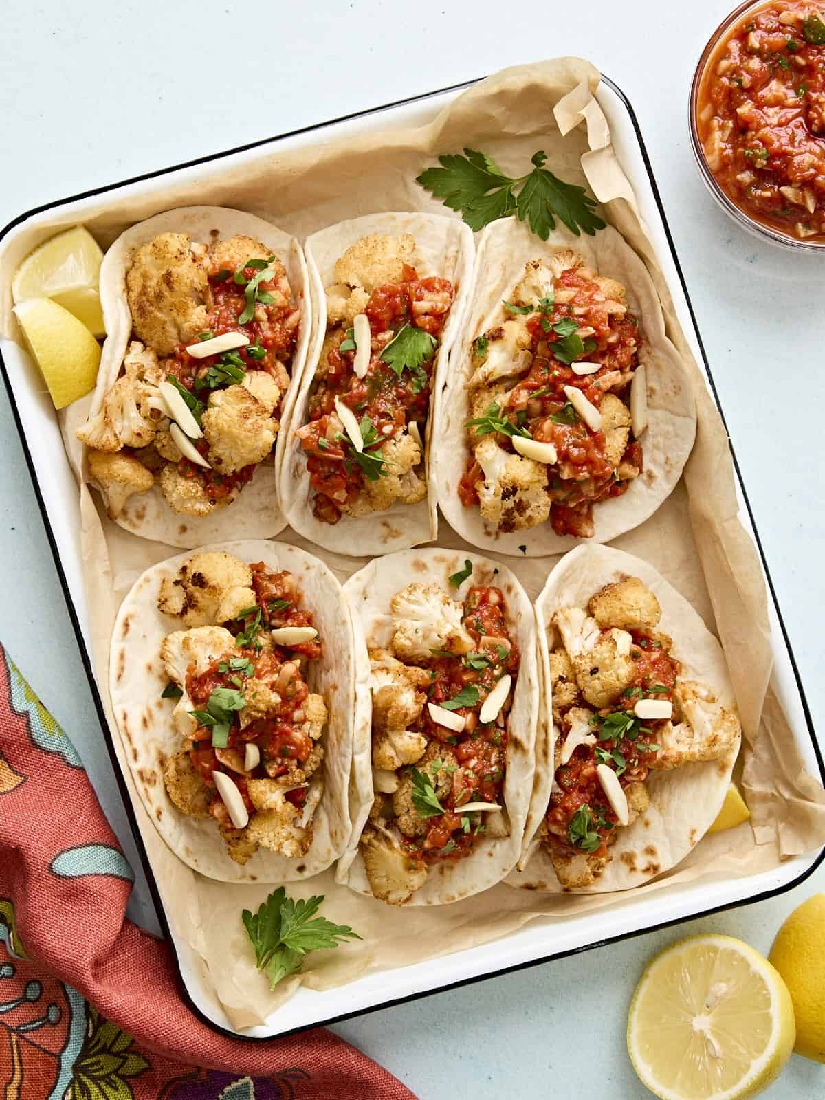 Tacos de chou-fleur à la sauce romesco dans un plat de cuisson recouvert de papier sulfurisé