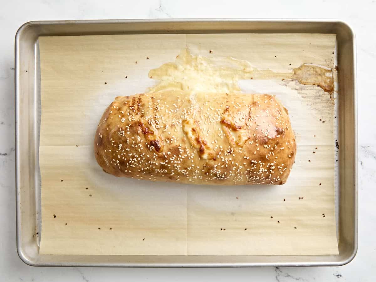 Rouleau de muffaletta fraîchement cuit sur une plaque à pâtisserie recouverte de papier sulfurisé