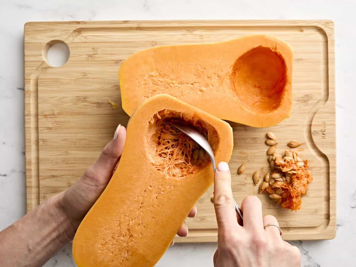 Une cuillère récupère la membrane filandreuse et les graines d’une moitié de courge musquée.