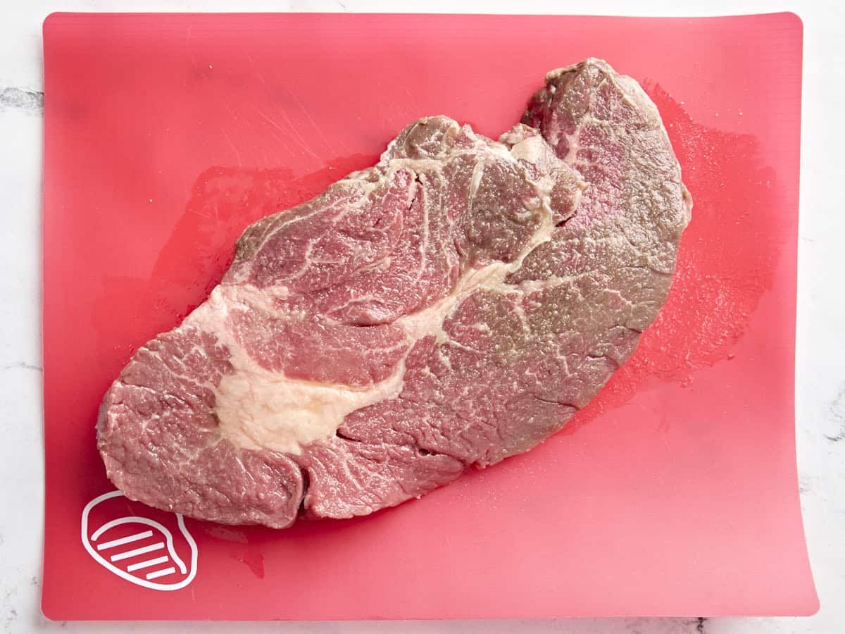 Rôti de paleron cru sur un tapis de viande rouge.