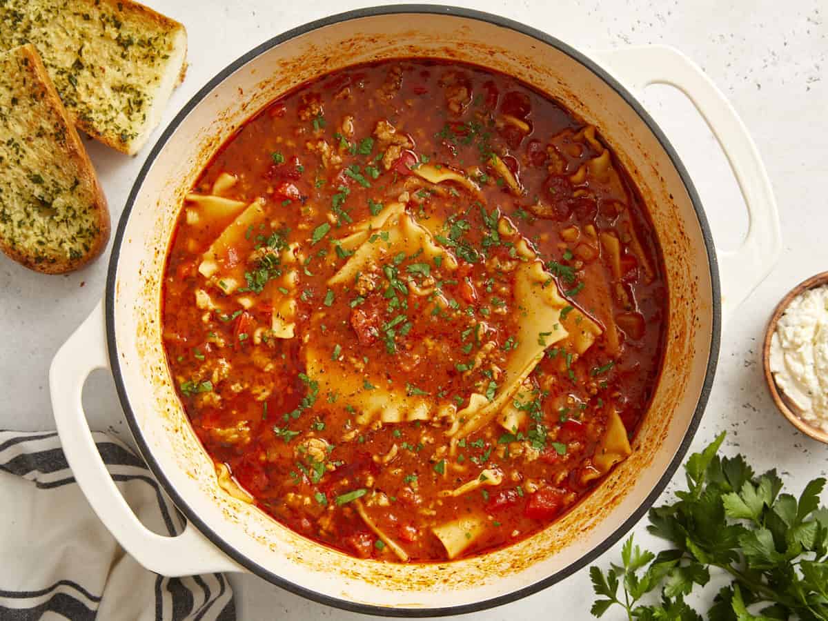 Vue aérienne de la soupe de lasagne dans une cocotte avec du pain à l'ail sur le côté.
