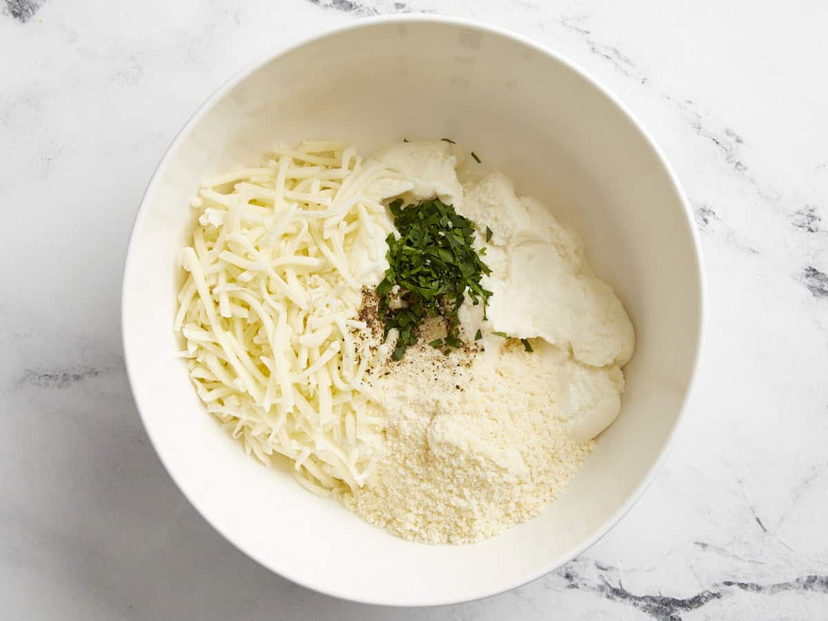 Ricotta, mozzarella et parmesan ajoutés dans un petit bol.