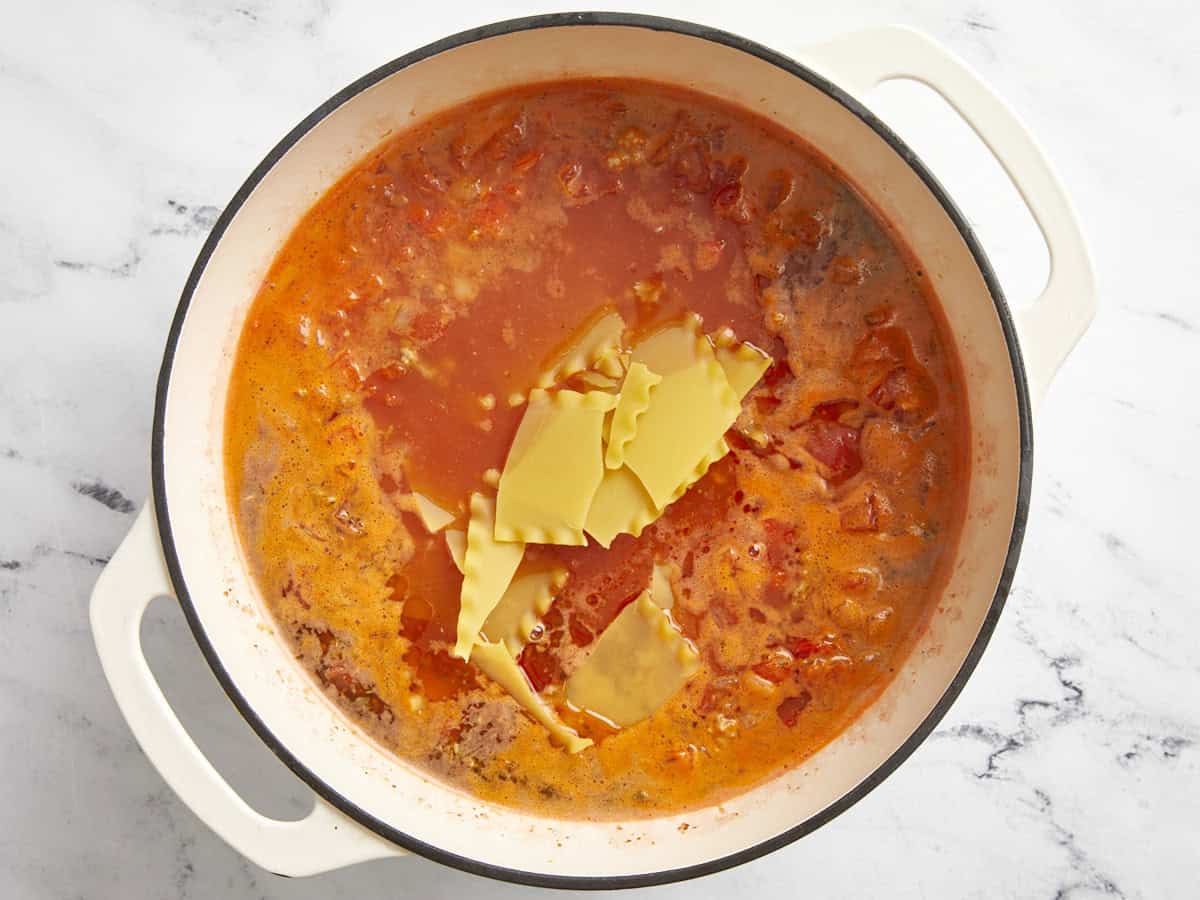 Nouilles de lasagne ajoutées à la marmite avec du bouillon de poulet.