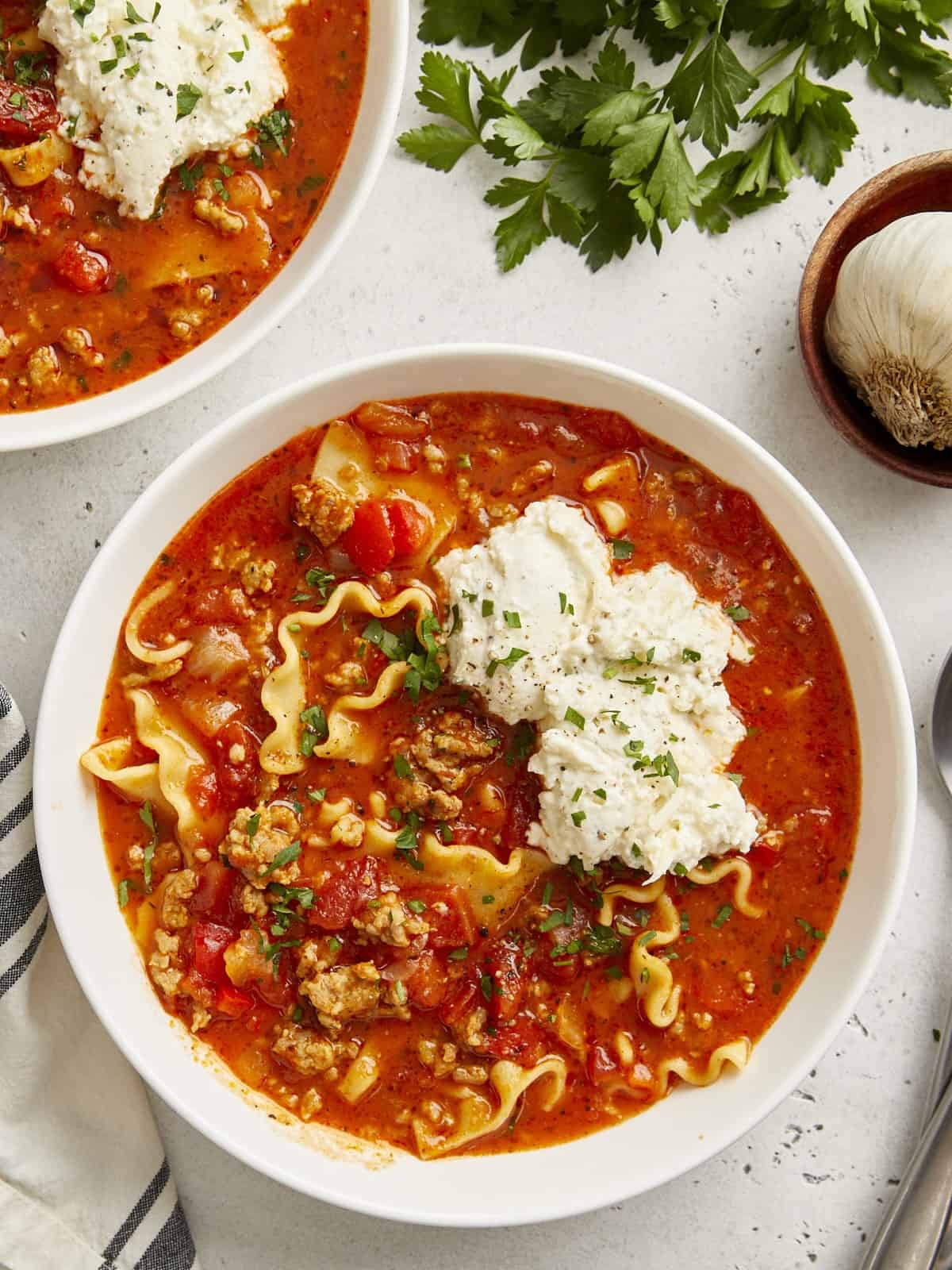 Vue aérienne de la soupe de lasagne dans un bol blanc avec un mélange de fromage ricotta sur le dessus.