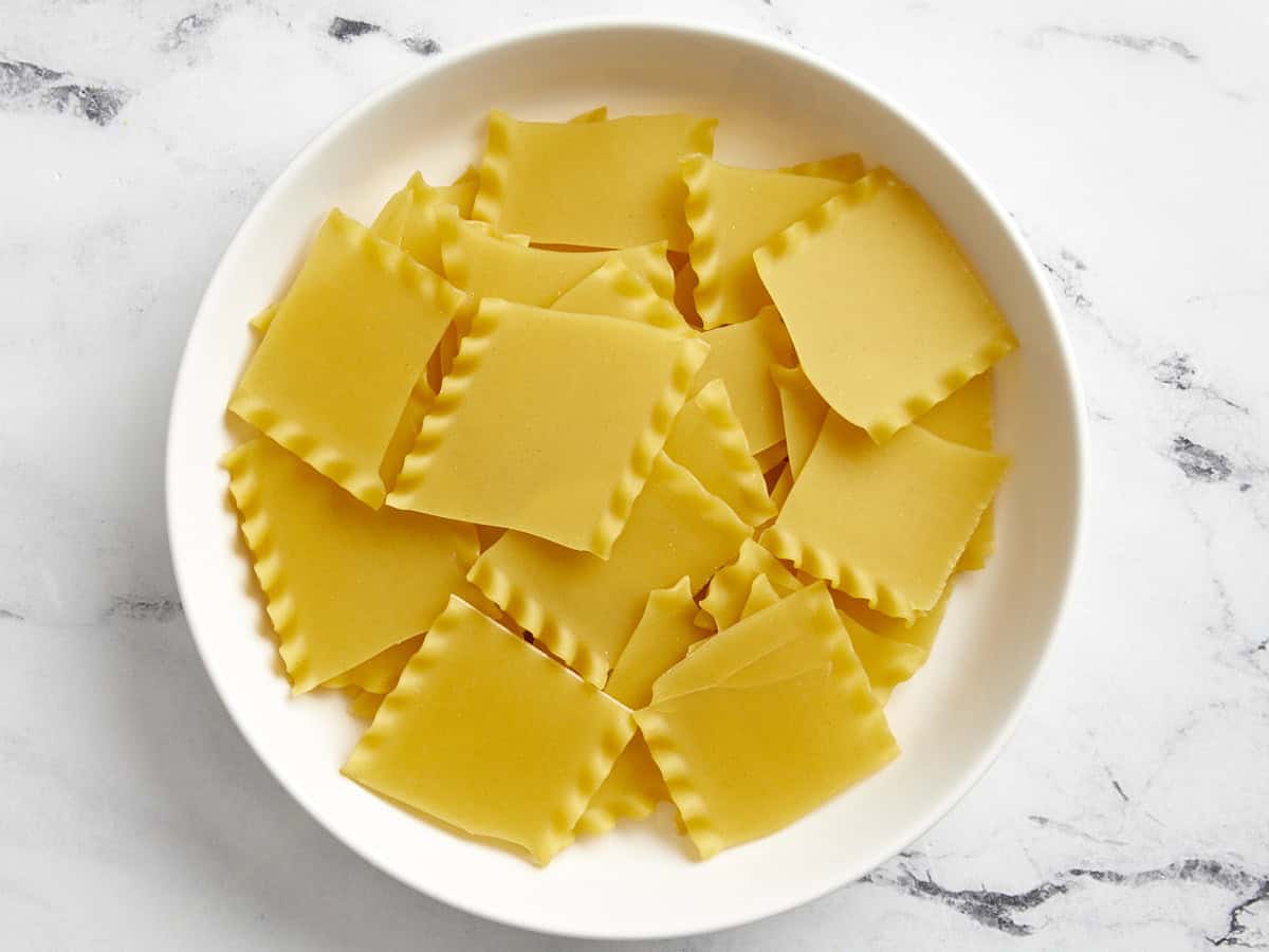 Nouilles de lasagne cassées dans un bol blanc.