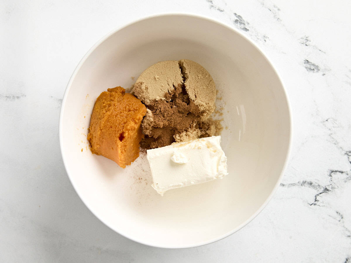 Sucre, purée de citrouille et fromage à la crème dans un bol à mélanger.
