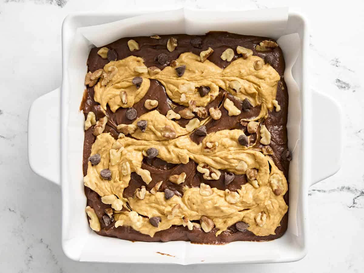 Pâte à brownie à la citrouille garnie de pacanes et de pépites de chocolat dans un plat allant au four.