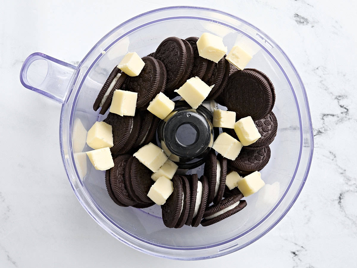 Oreos et beurre en cubes dans un robot culinaire.
