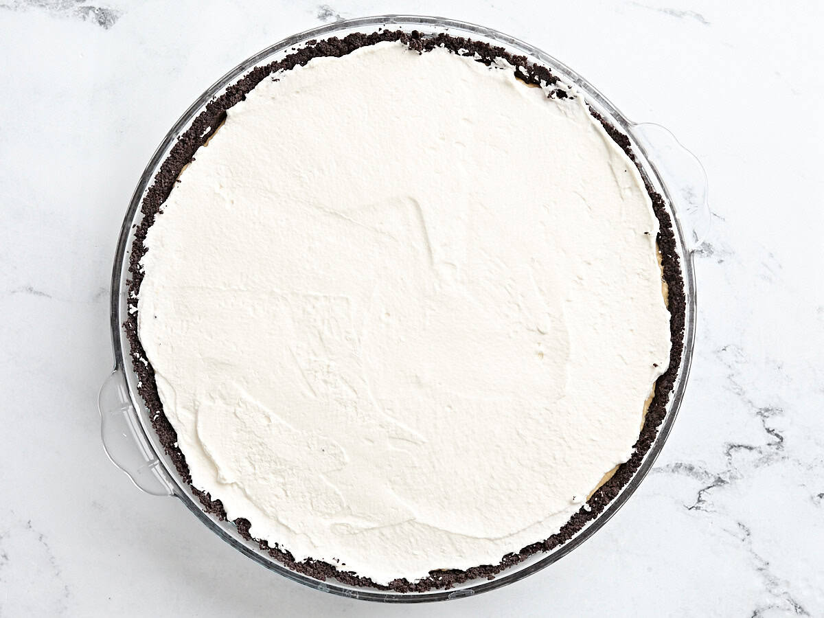 Vue aérienne d'une tarte au beurre de cacahuète garnie de crème fouettée.