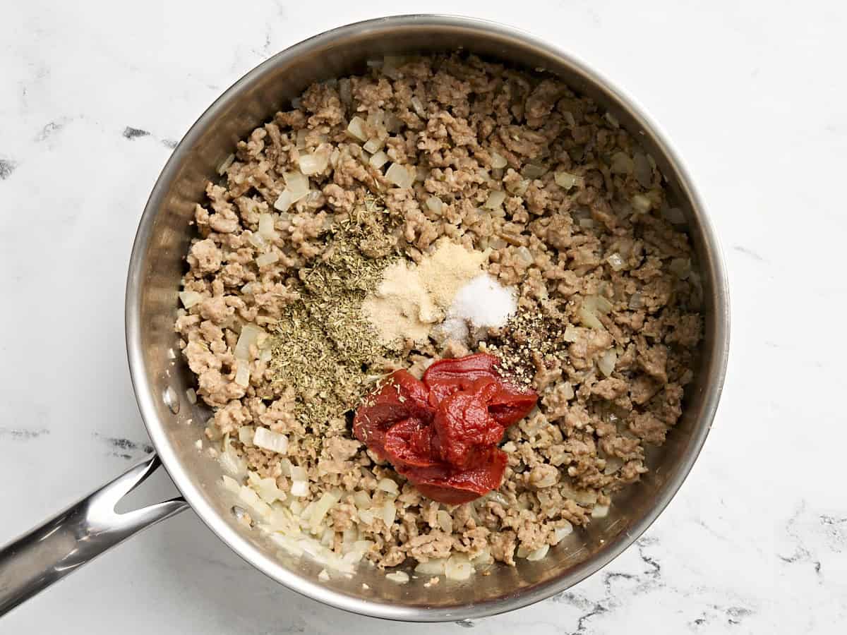 Pâte de tomate et assaisonnement ajoutés à la poêle.
