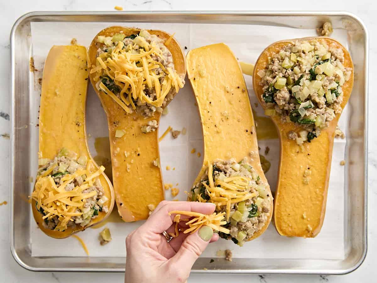 Une main saupoudrée de courge musquée farcie de fromage râpé.